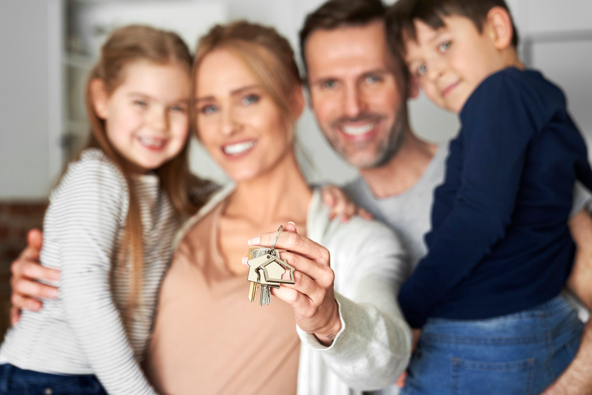 Happy family holding new house keys, smiling at the camera.