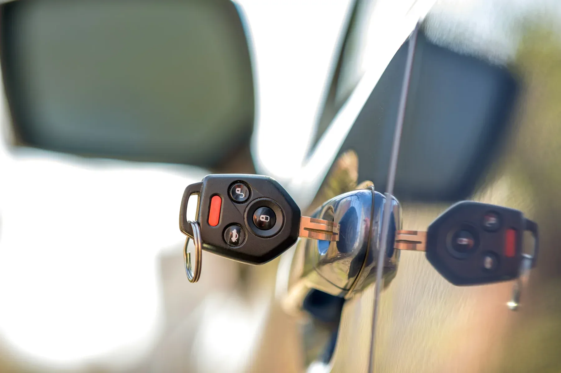 Car key in door lock with remote fob attached.