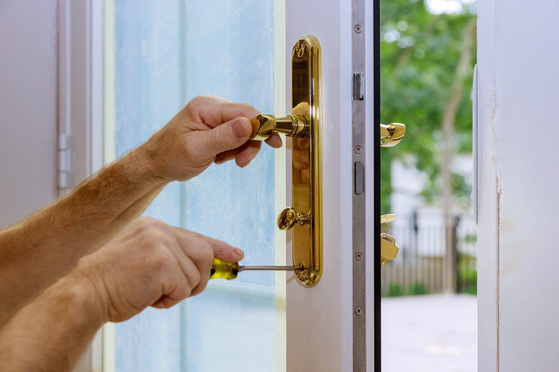Close-up of hands installing a new golden door handle and lock.