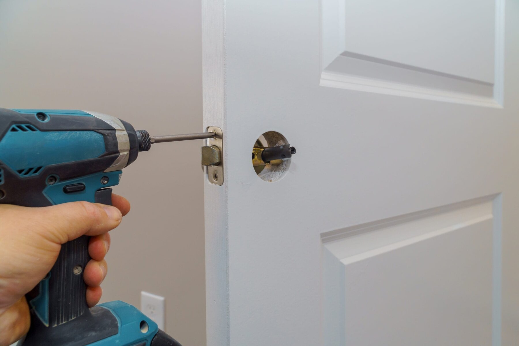 Hand using a power drill to install a door lock