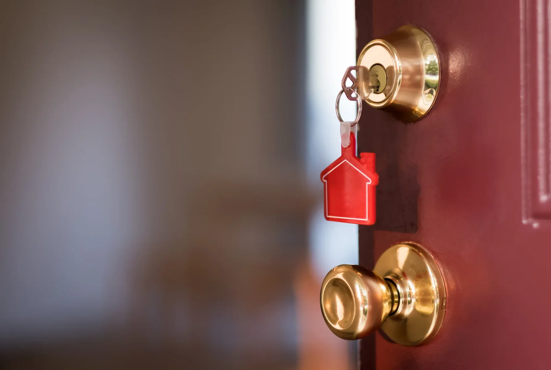 Key with a red house-shaped keychain in a door lock