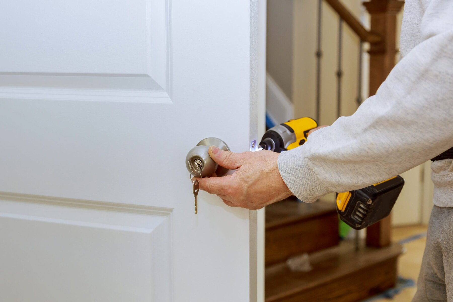 Person installing a doorknob with a drill on a white door