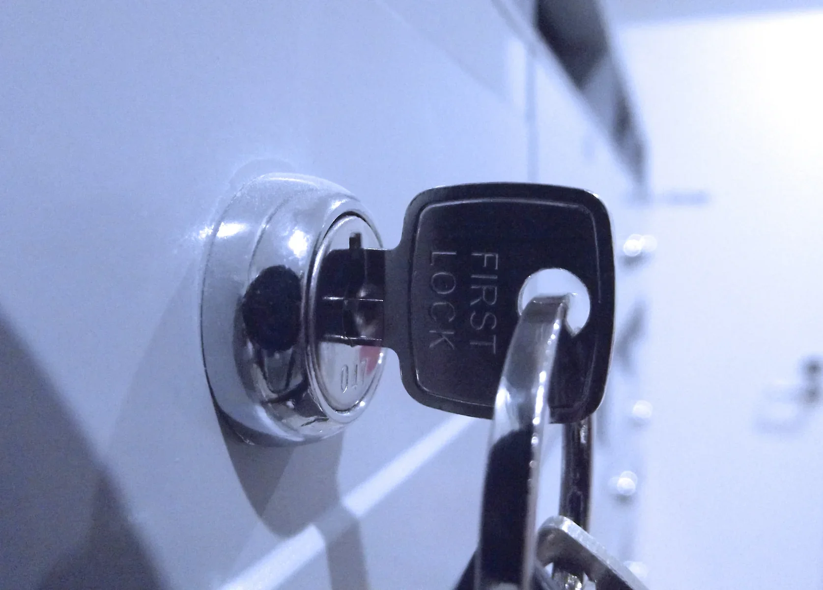 Close-up of a silver key inserted into a lock on a light-colored surface