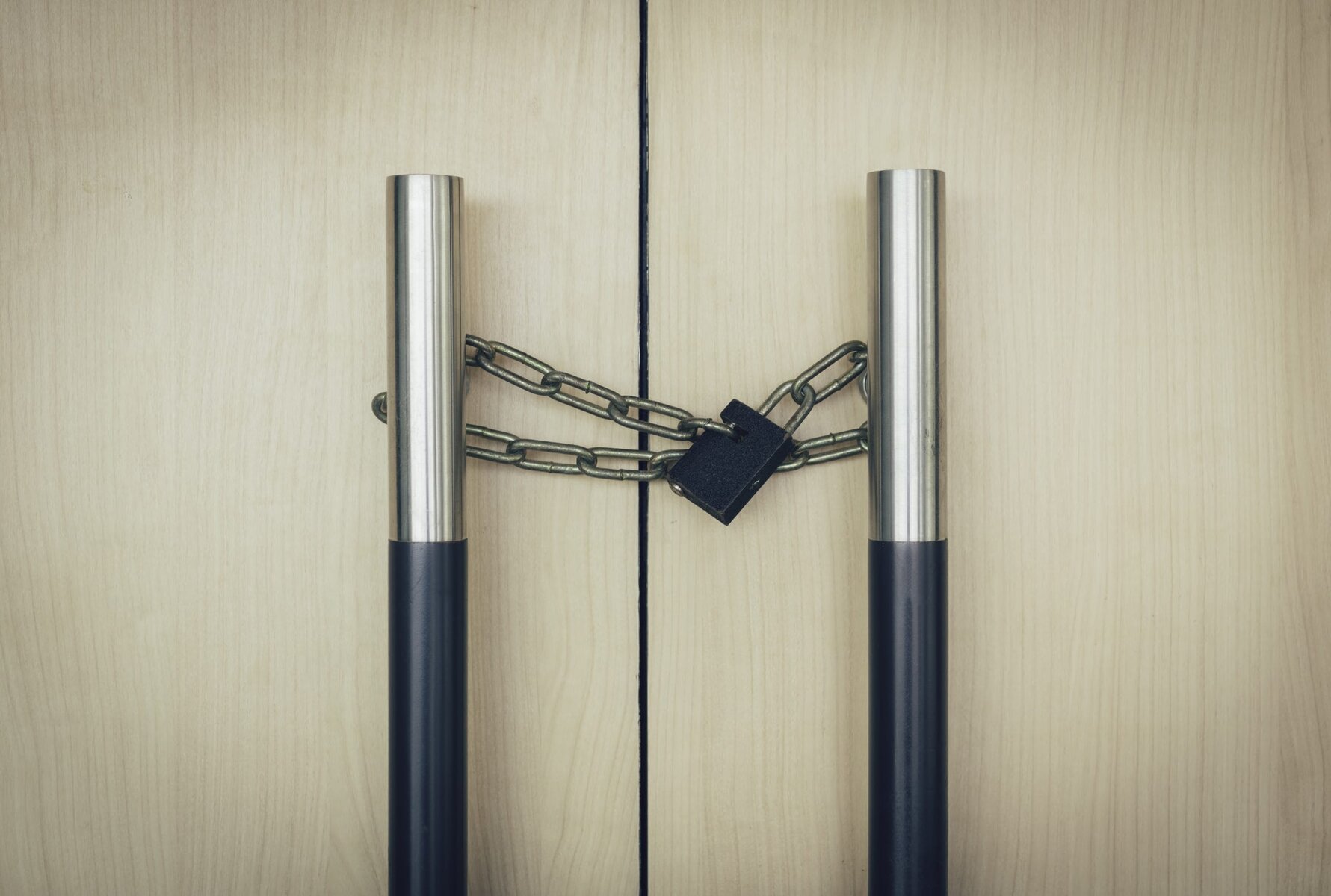 Two wooden doors with metal handles chained and locked together.