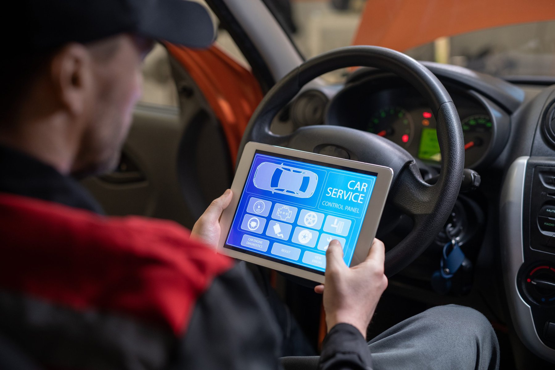 Mechanic using a tablet with car service control panel in a vehicle