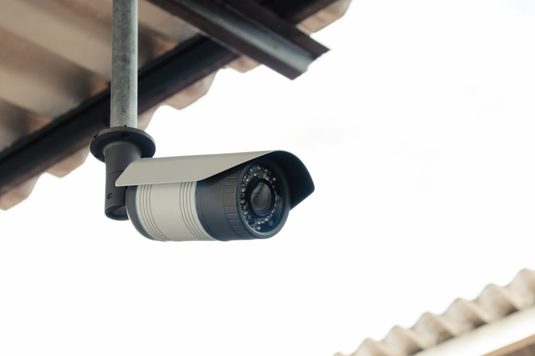 Security camera mounted under a corrugated roof, pointing forward.