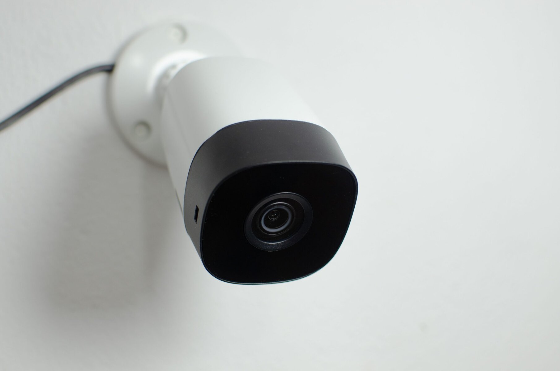 White and black security camera mounted on a white wall