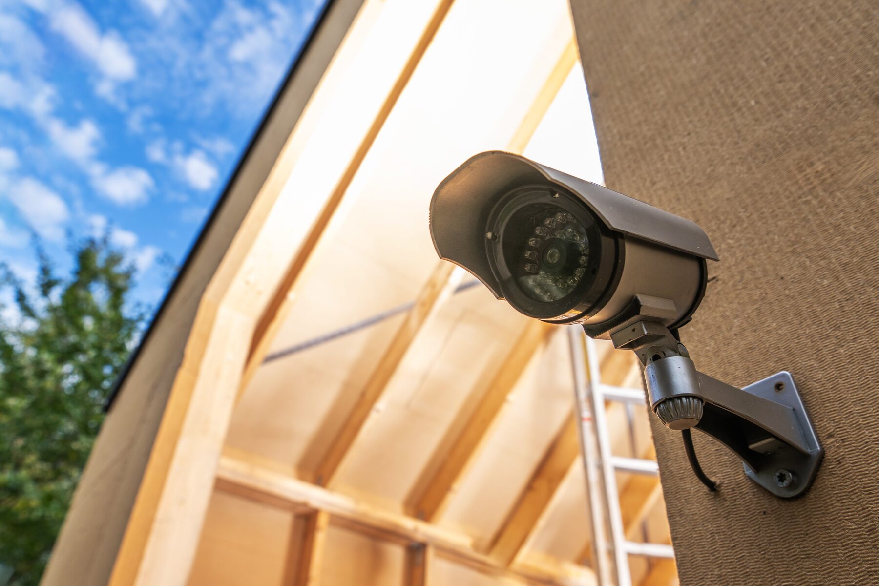 Security camera mounted on a building, blue sky with clouds