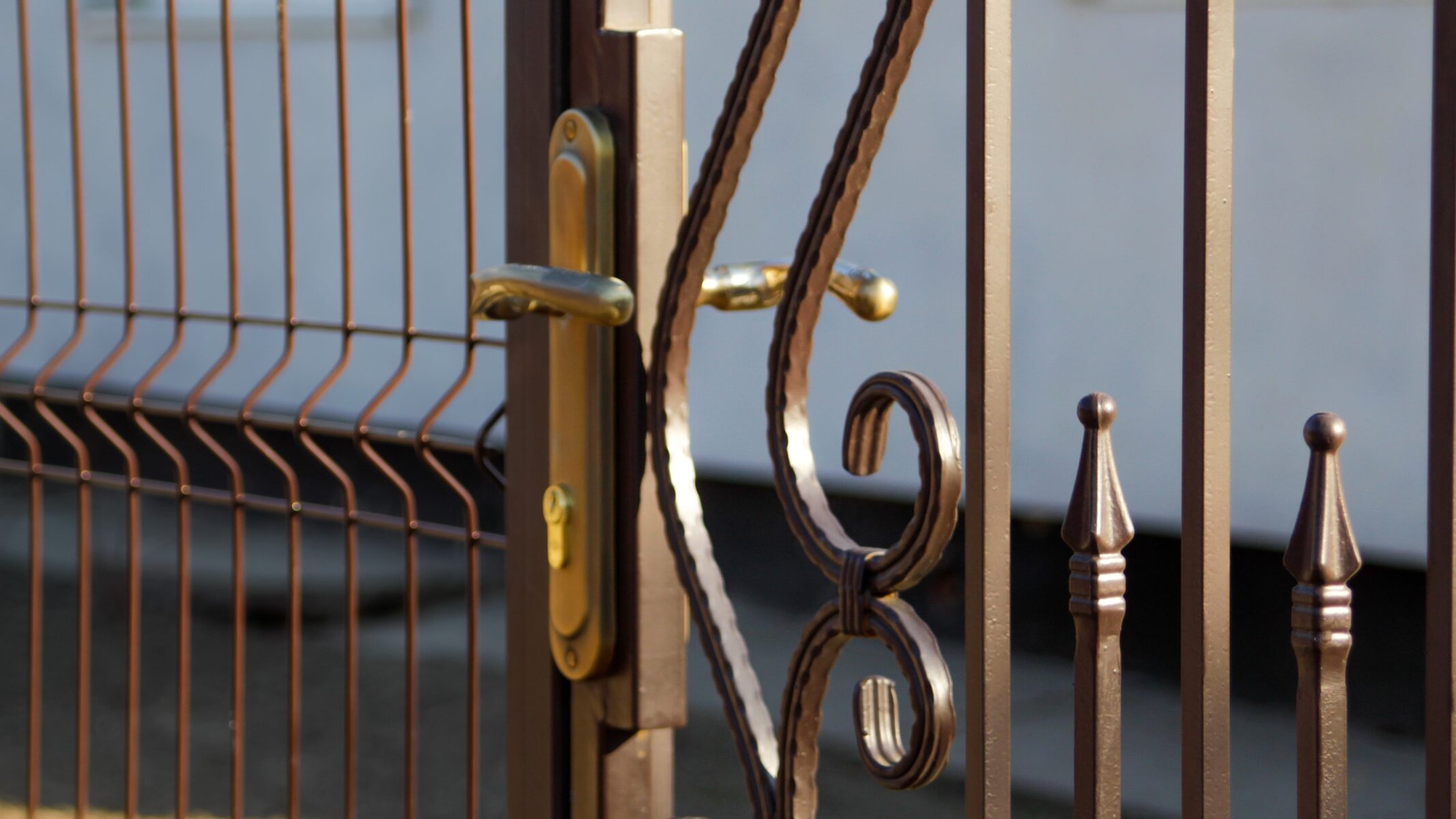 Close-up of a brown metal fence and gate with a golden handle.