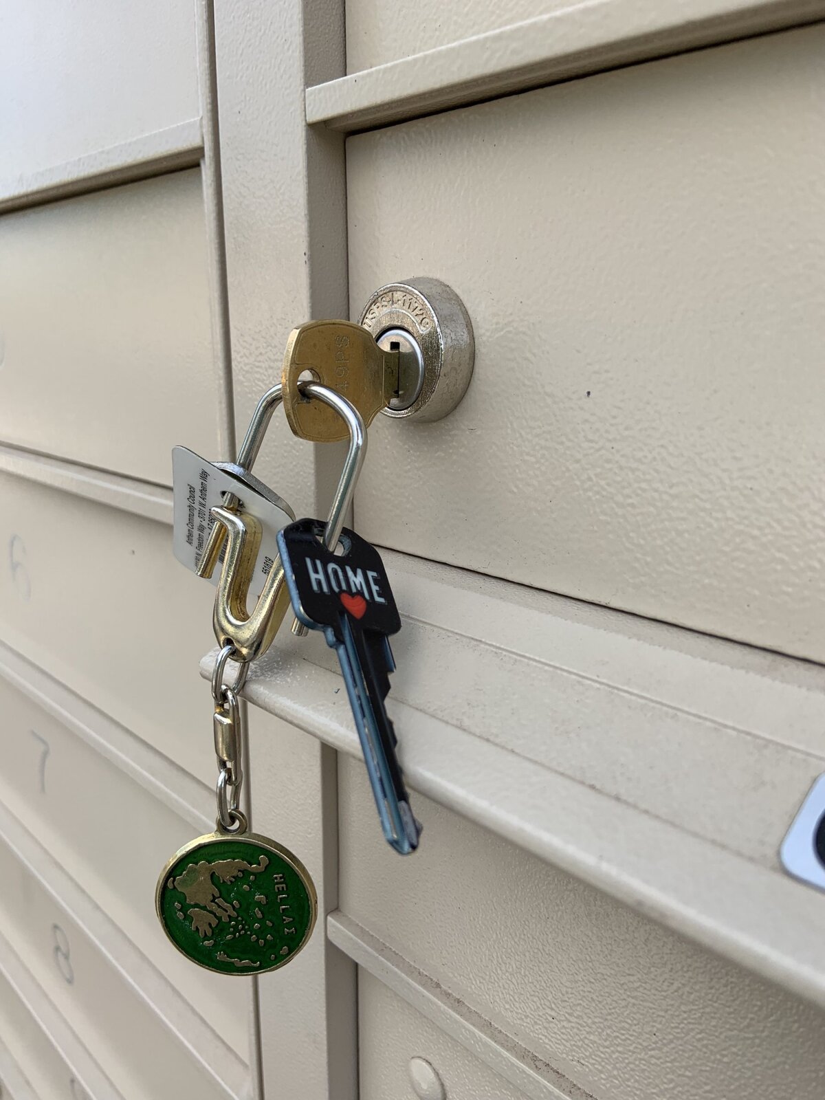 Keys in a mailbox lock, including one with 'HOME' and a heart.