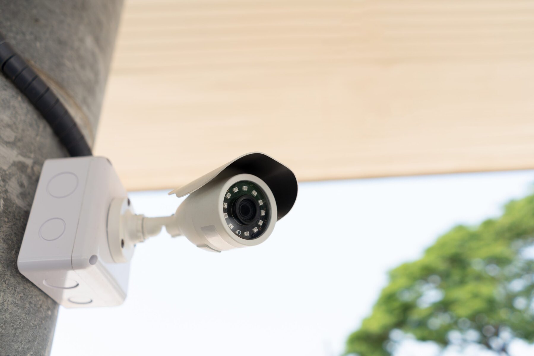 White security camera mounted on a gray pole with a light background