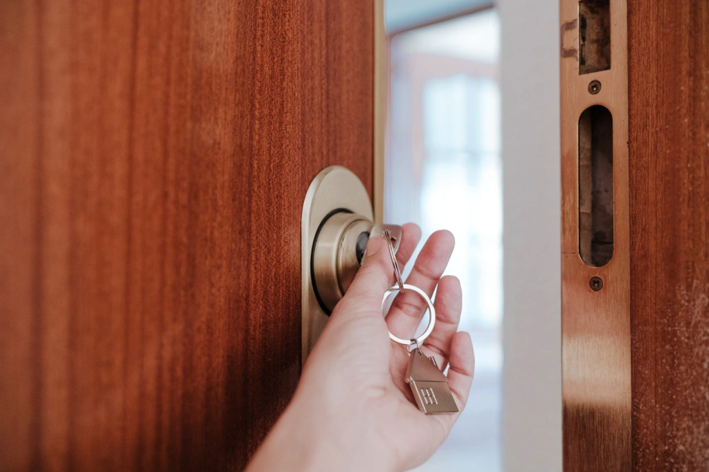 Hand inserting a key into a wooden door lock