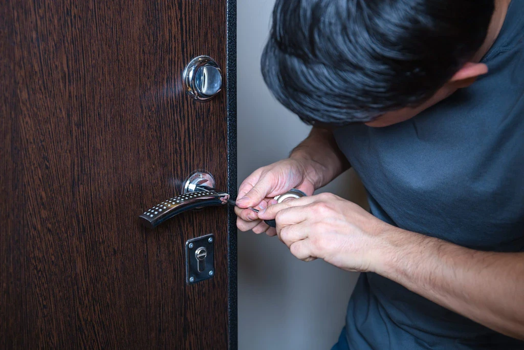 Man attempting to pick a door lock with tools