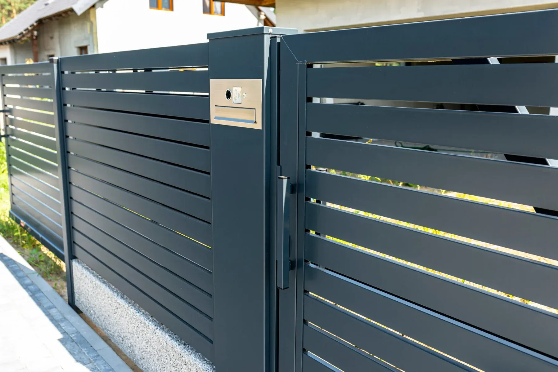 Modern dark gray metal fence with horizontal slats and a built-in mailbox.