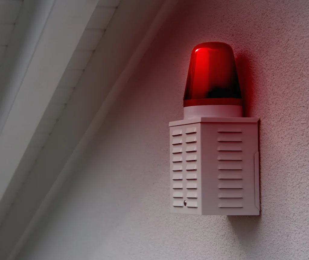 Red alarm light flashing on a white wall