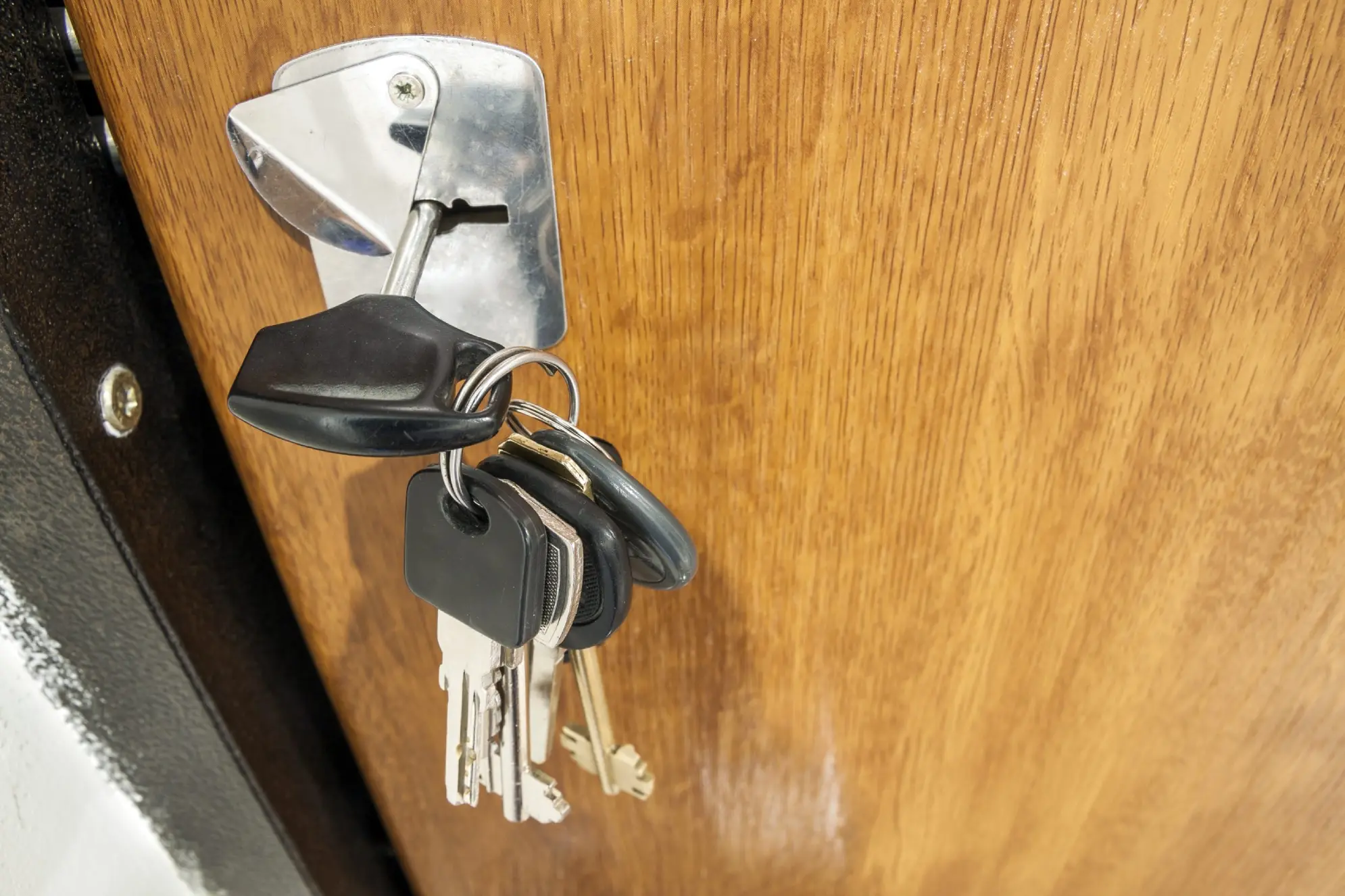 Keys in a silver lock on a wooden door