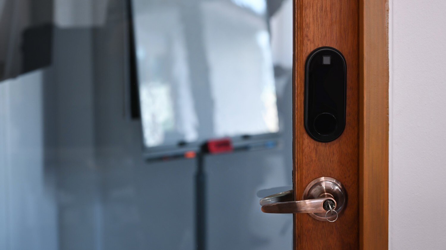 Smart lock and doorknob on a wooden door, with a blurred room in the background.