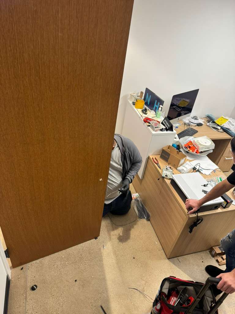 Two people installing a wooden door in an office space.
