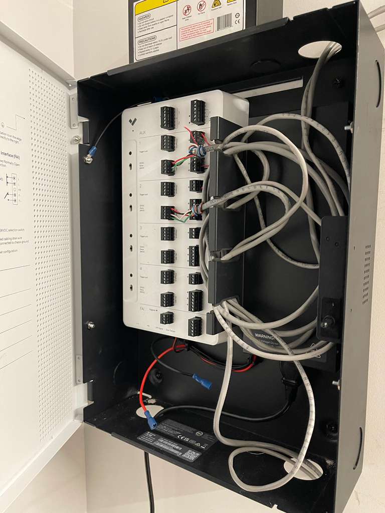 Open electrical box with white module and tangled gray cables
