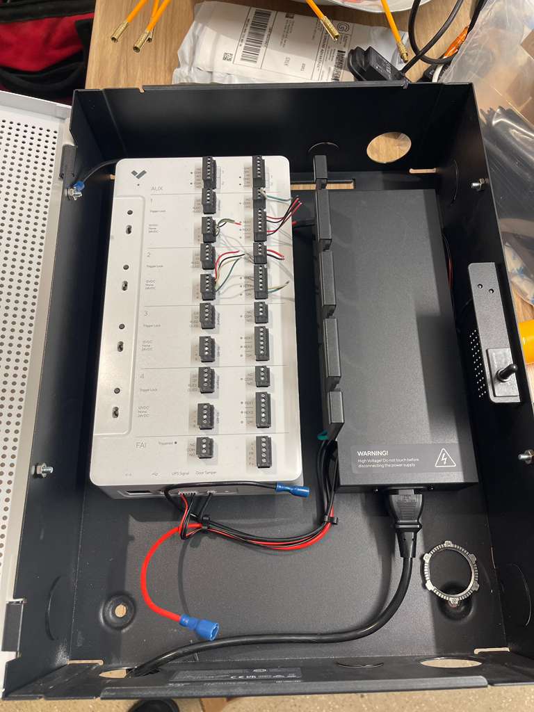 Open electrical box with white circuit board and black power supply.