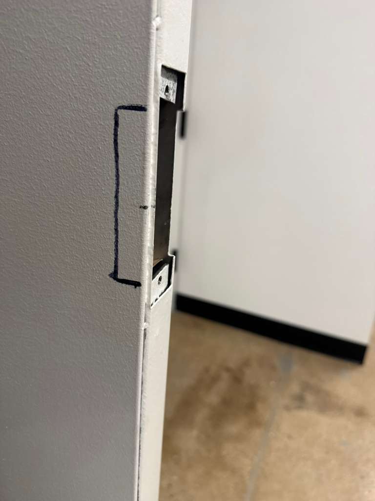 Close-up of a metal door frame with a cut-out for a lock mechanism.