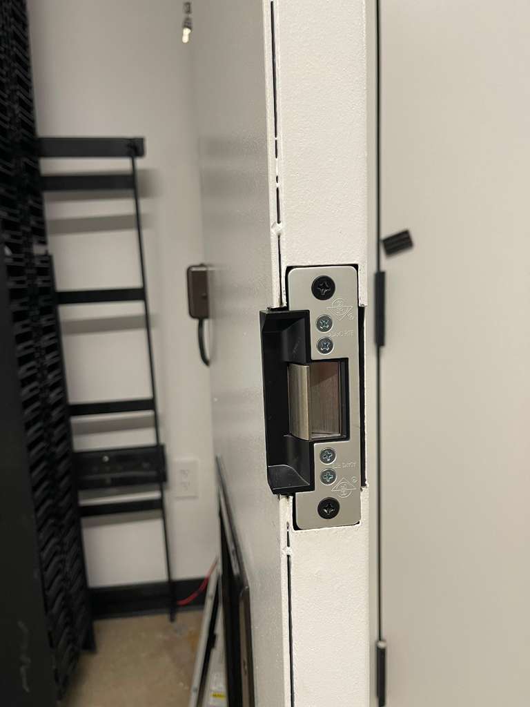 Close-up of a white door jamb with an electric strike plate installed.