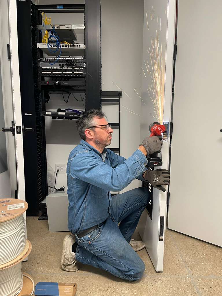 Man in denim grinding metal on a door with sparks flying