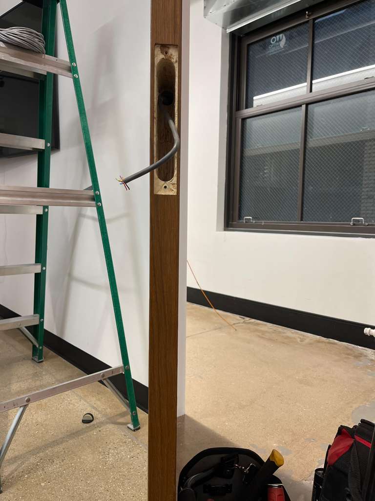 Door frame with exposed wiring, a ladder, and a window.