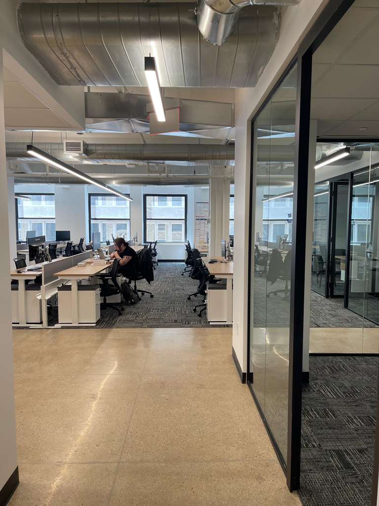 Modern office space with desks, computers, and a person working