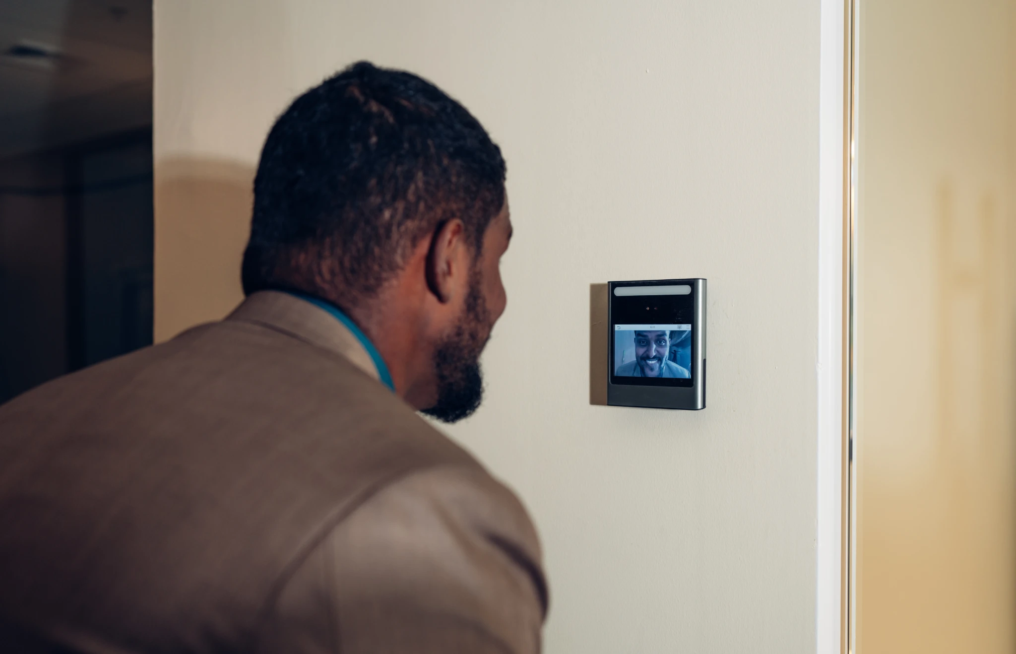 Man looking at a video intercom with a smiling man on screen