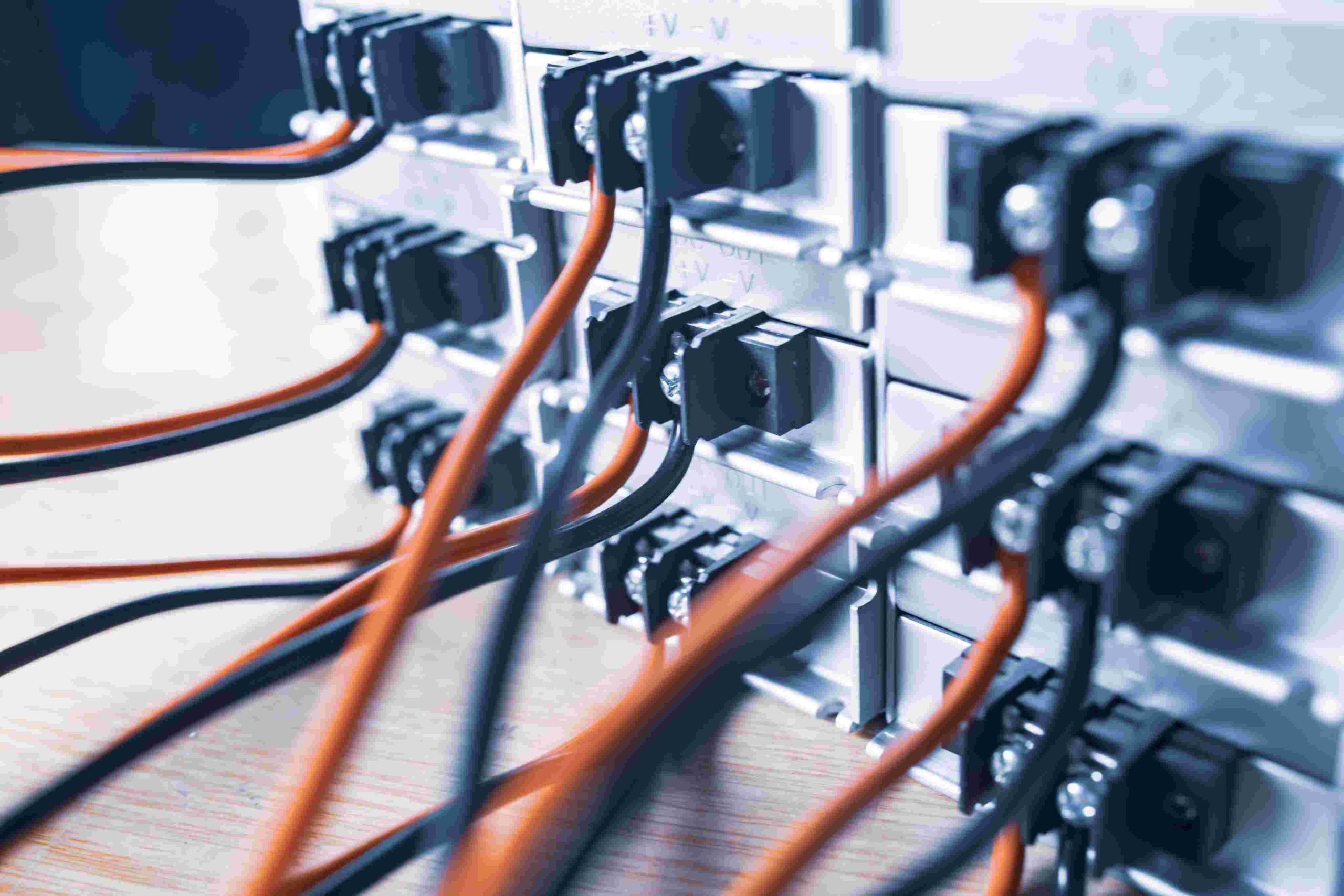 Close-up of numerous black and orange wires connected to a server rack.