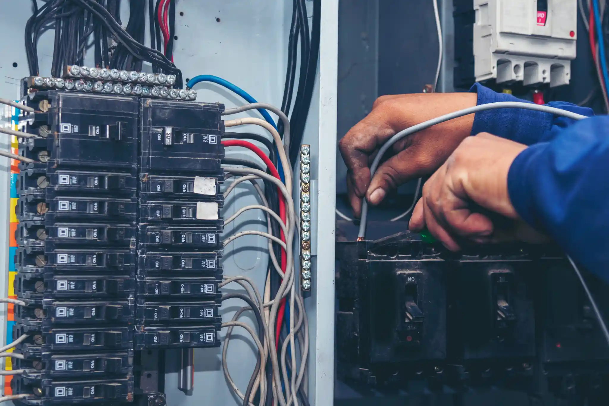 Close-up of hands working on an electrical circuit breaker box