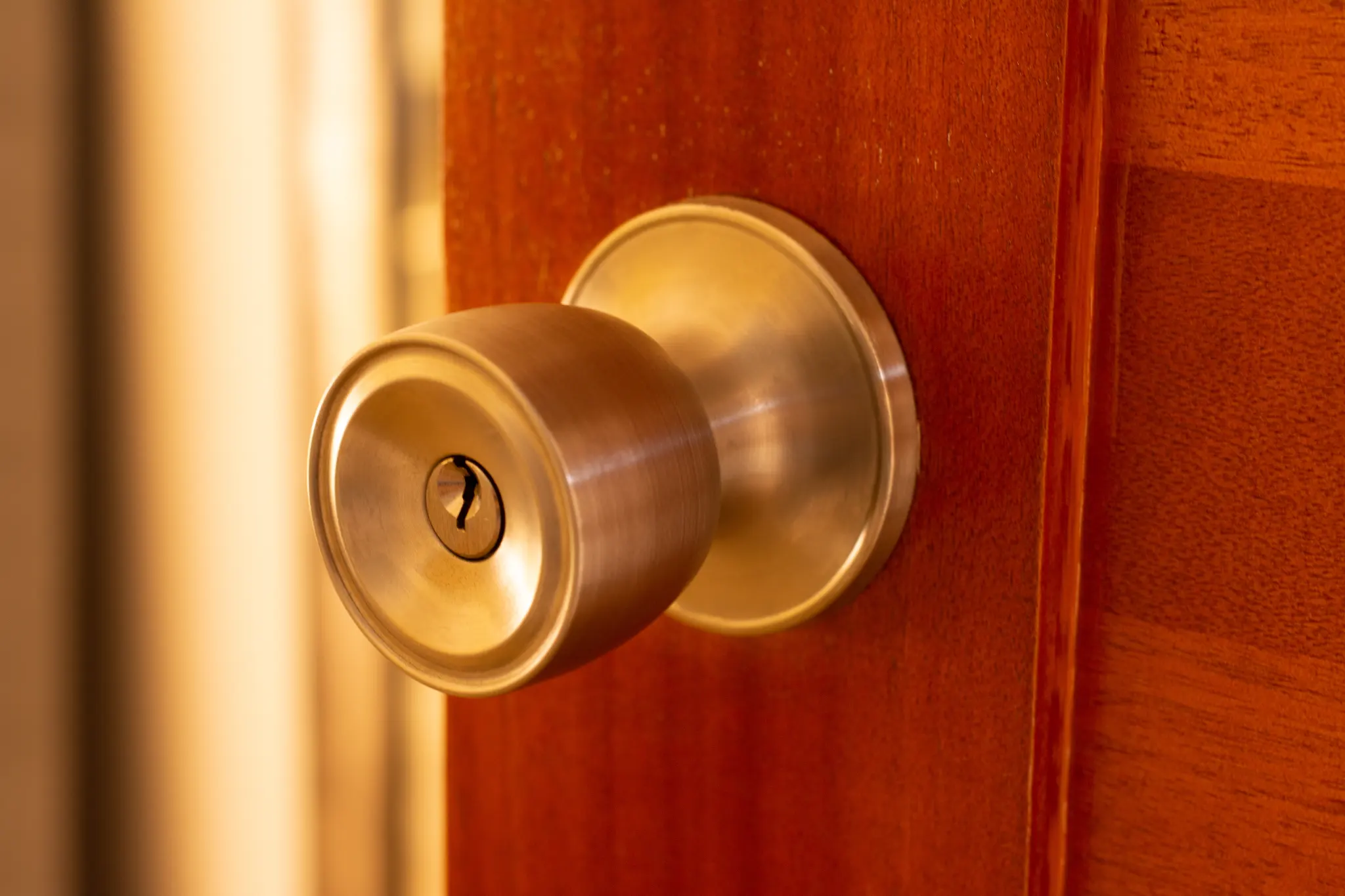 Close-up of a brass doorknob with a keyhole on a wooden door.
