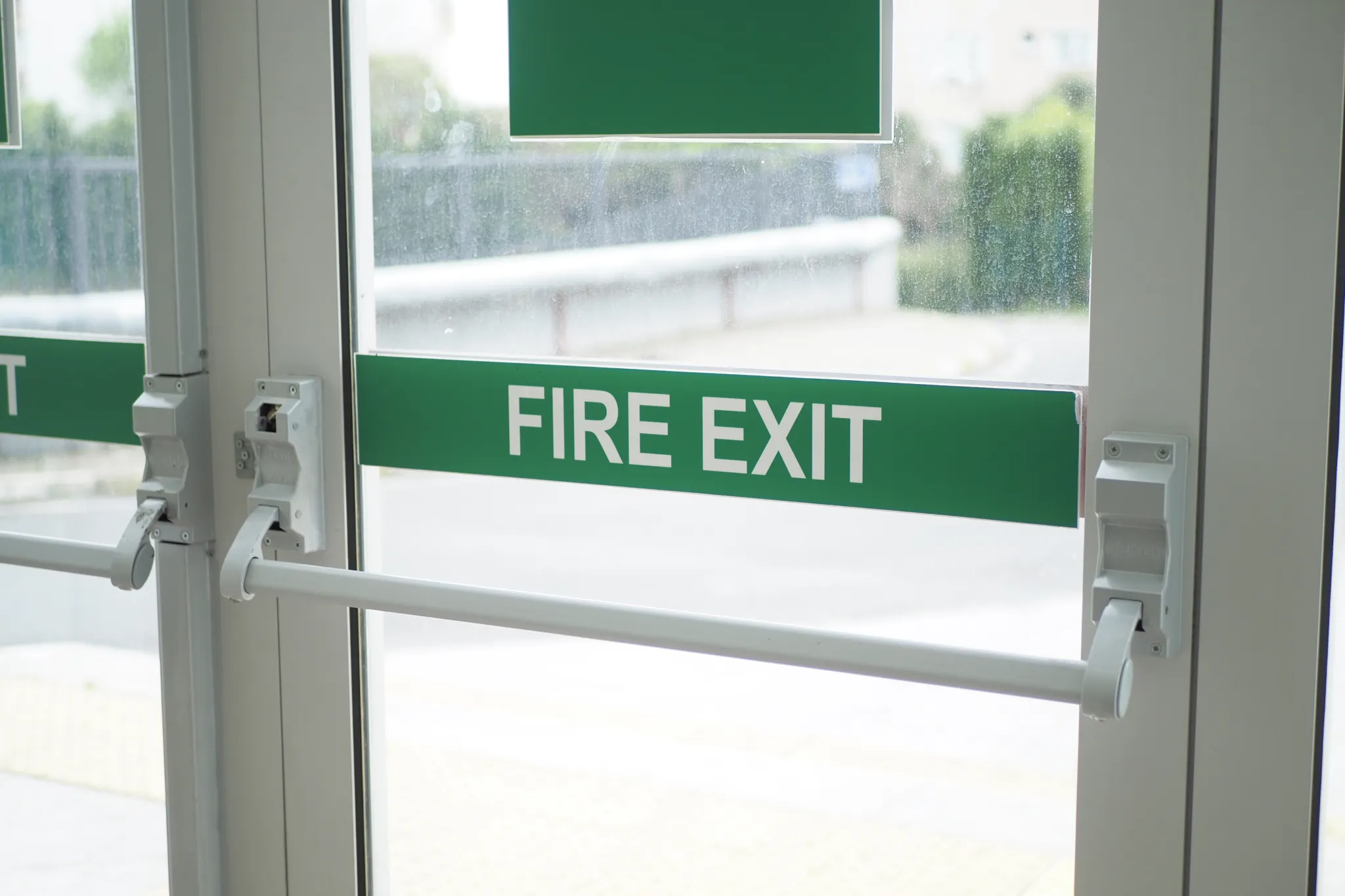 Close-up of a white fire exit door with a green 'FIRE EXIT' sign.