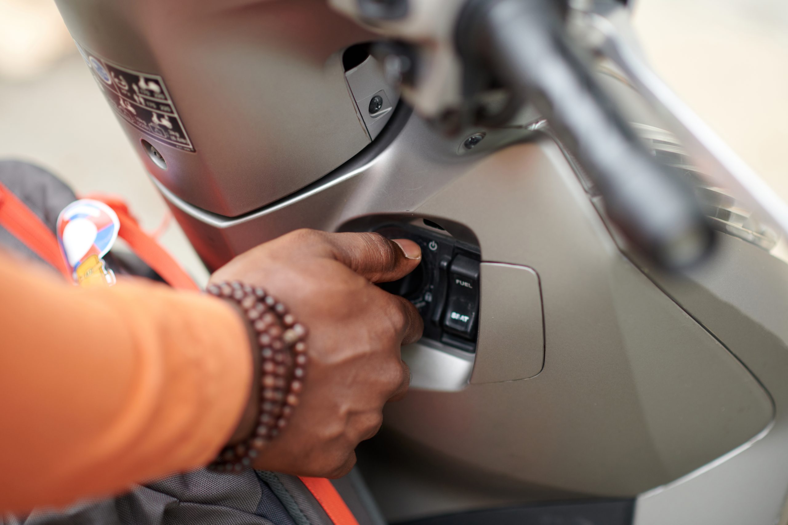 Close-up of a person's hand inserting a key into a scooter ignition