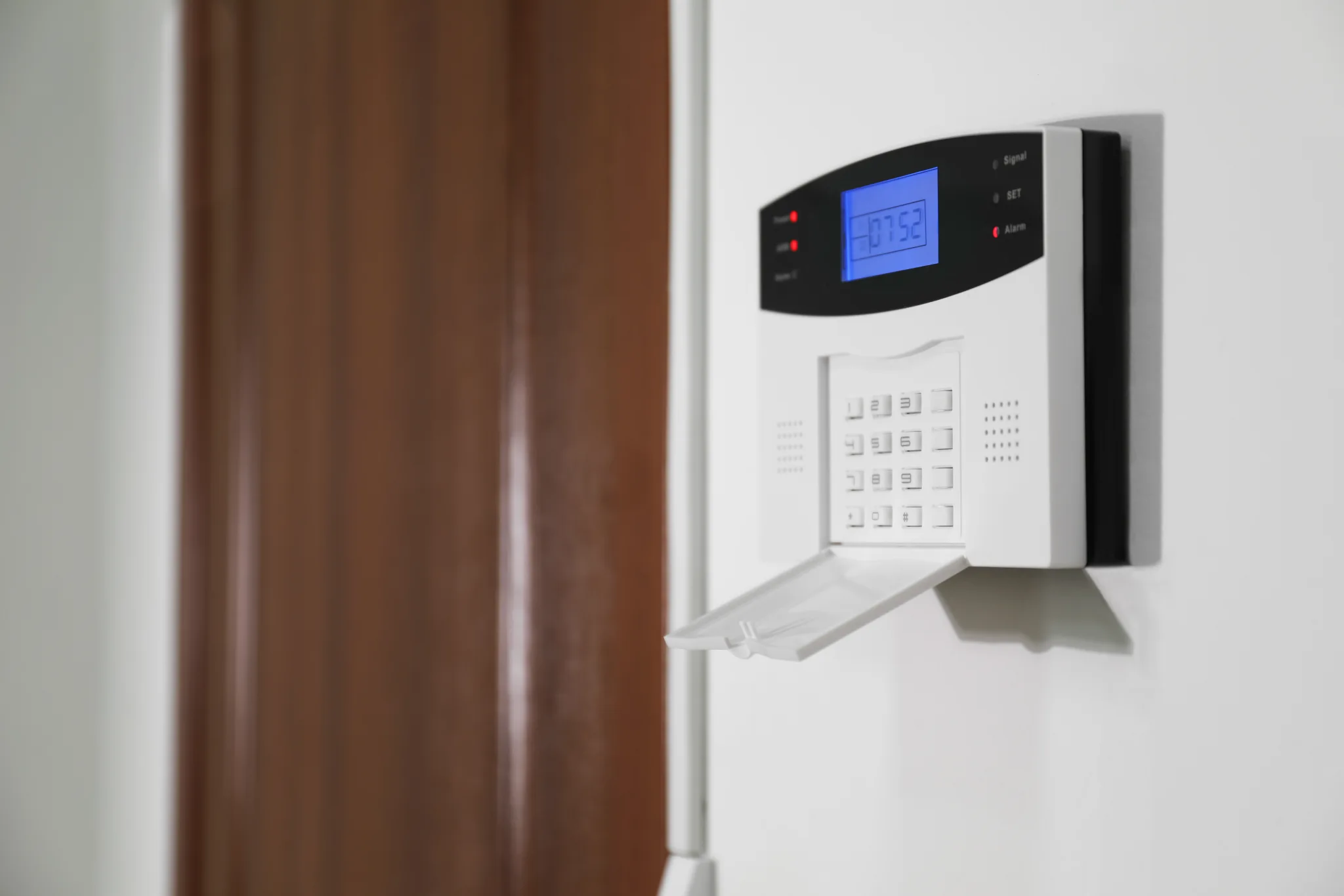 Close-up of a white security alarm system on a wall.