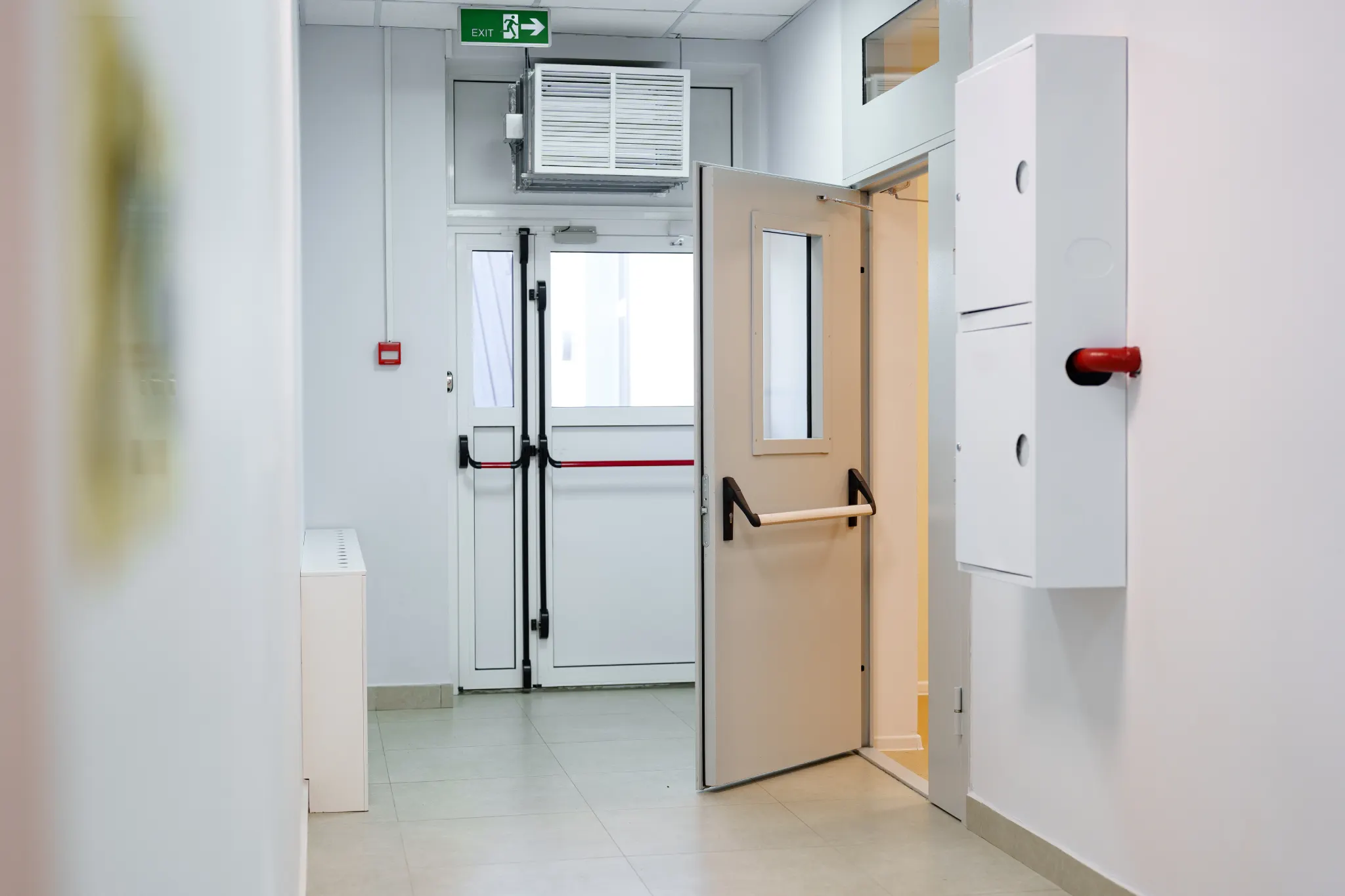 Emergency exit with two white doors and a fire extinguisher cabinet