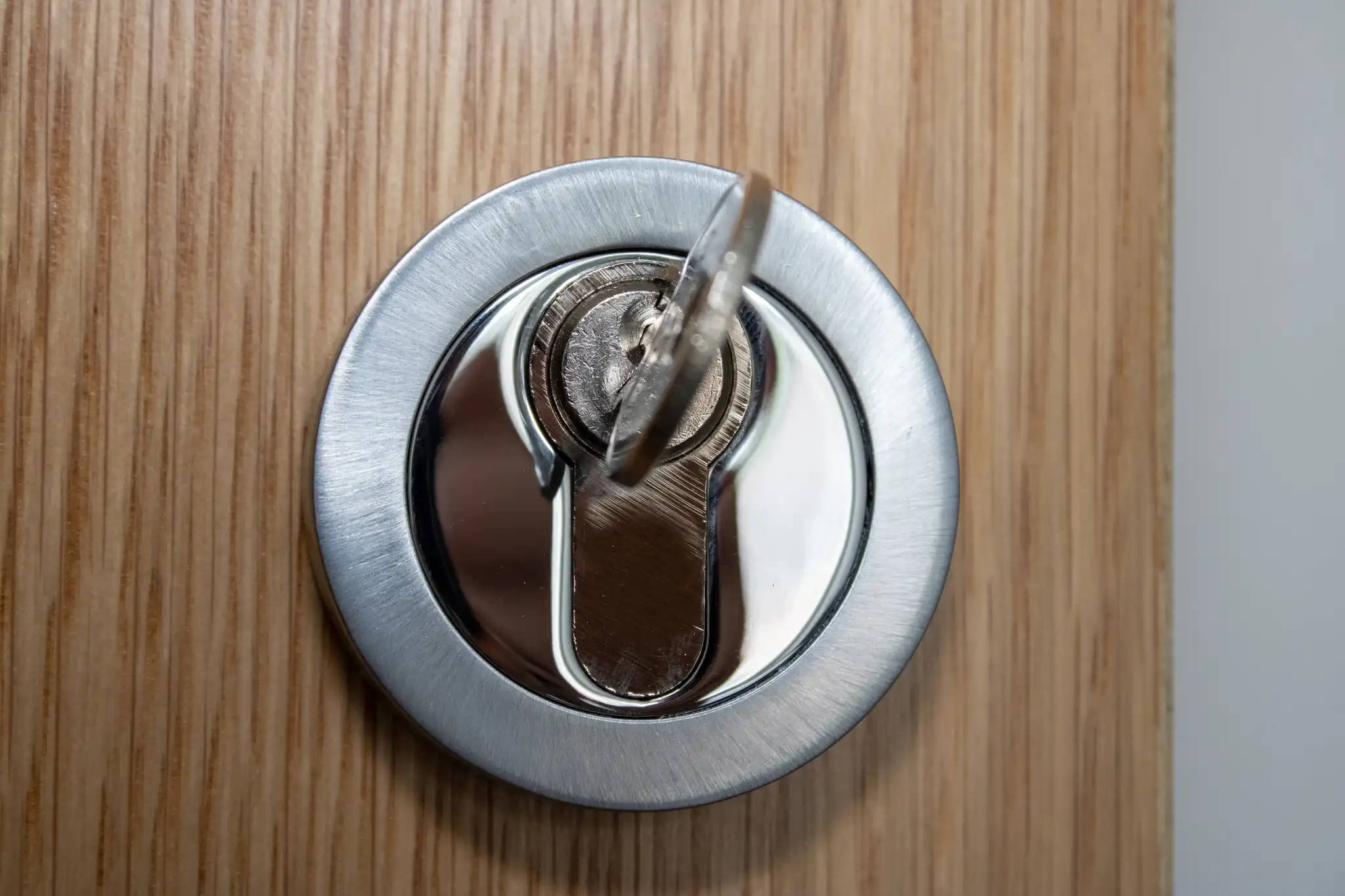 Close-up of a silver door lock with a key inserted into the keyhole.