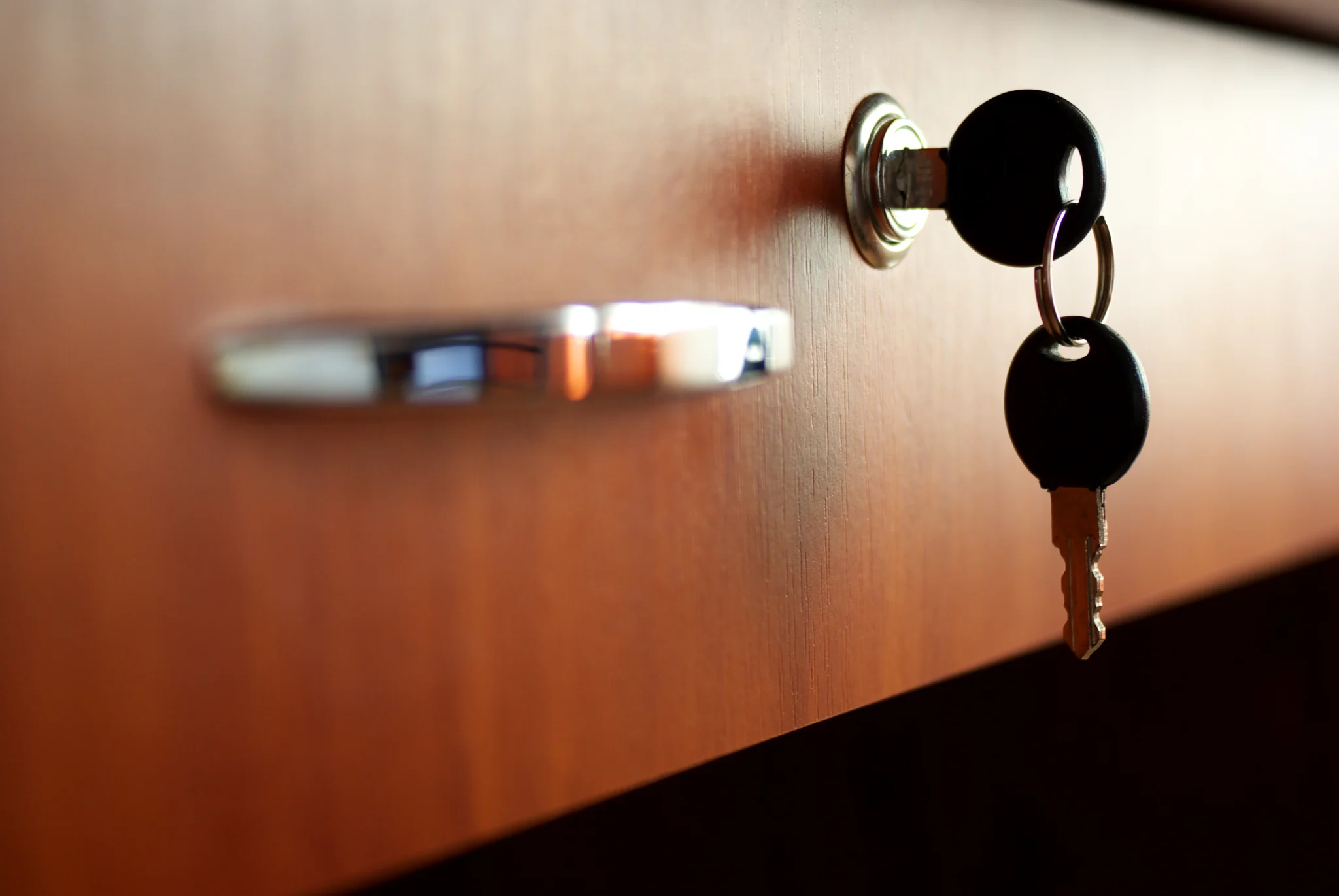 Close-up of a key in a lock on a wooden drawer.