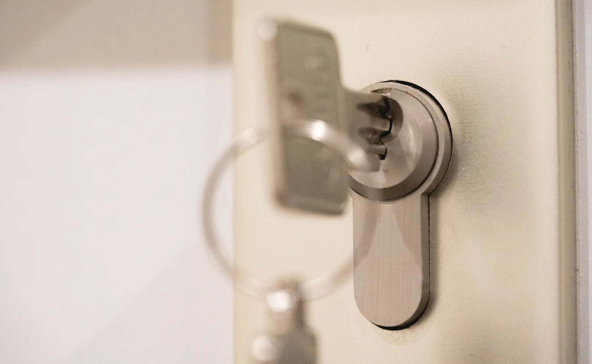 Close-up of a silver key inserted into a door lock.