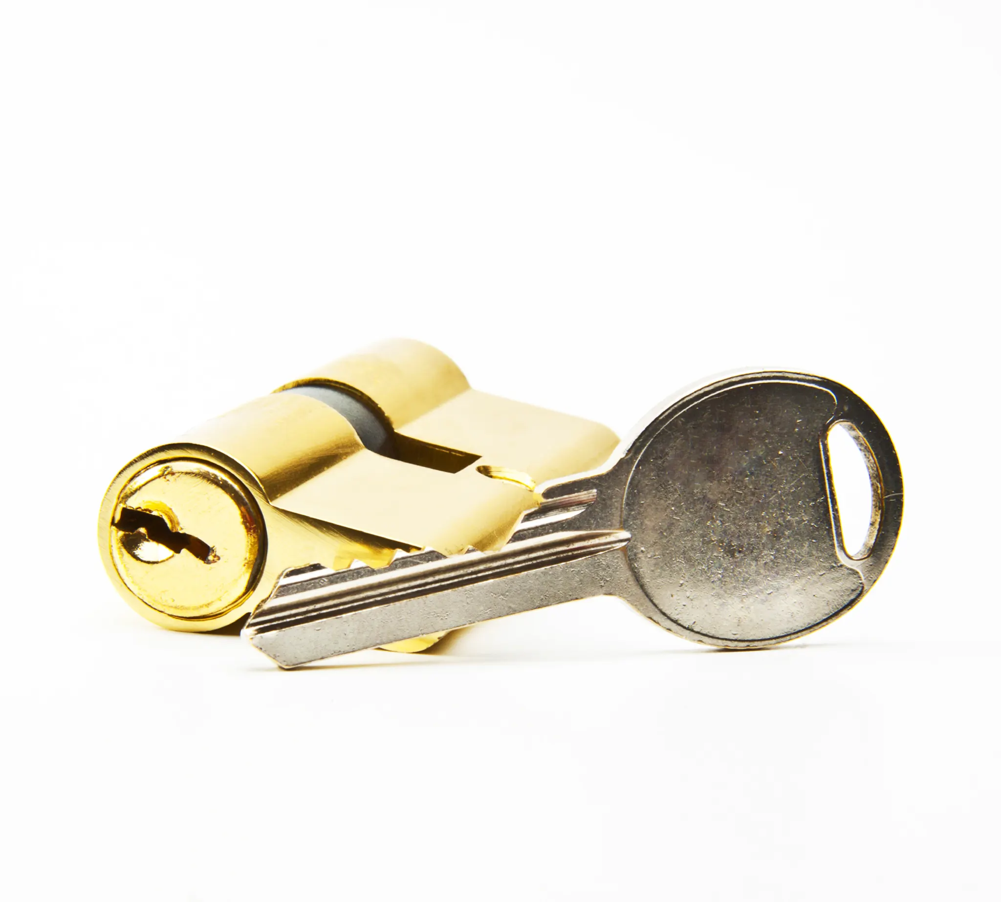 Close-up of a golden door lock cylinder and a silver key on a white background.