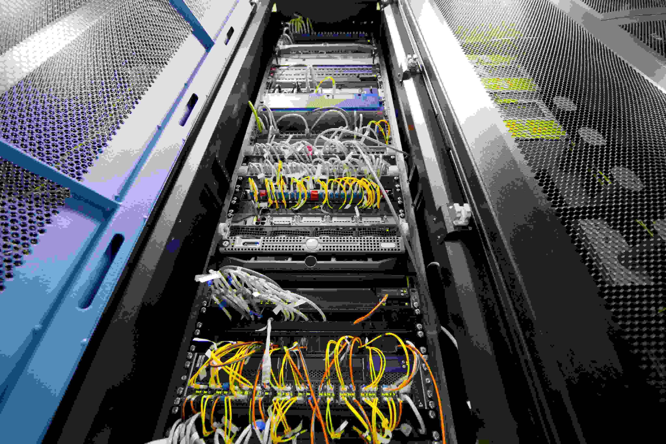 Close-up of server racks with numerous colorful cables and blinking lights.