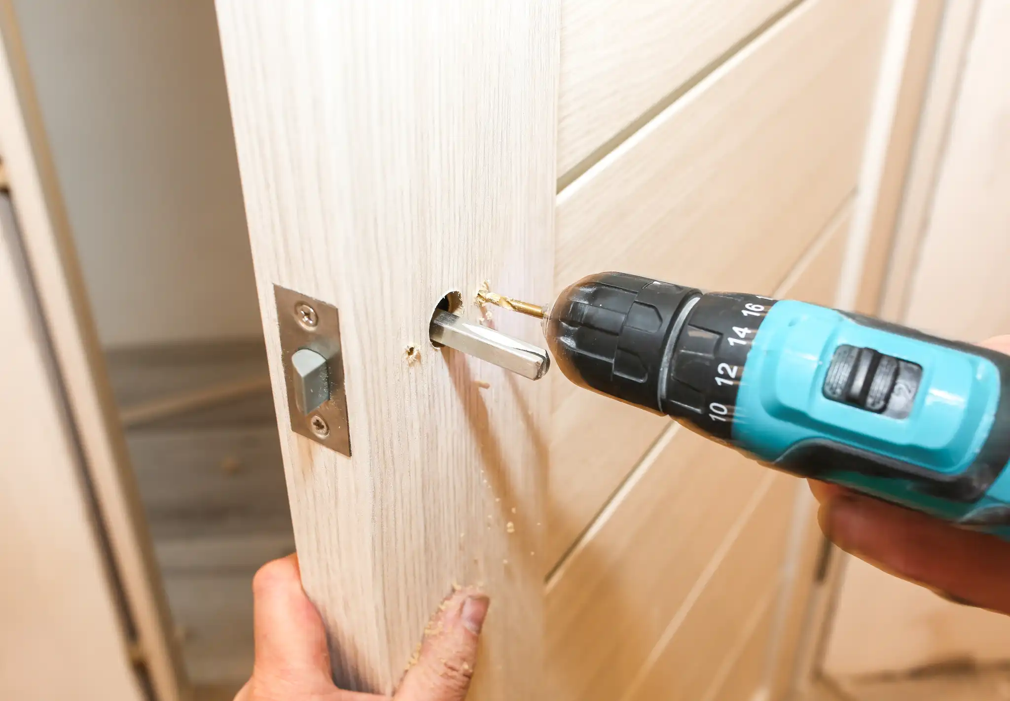 Close-up of a person drilling a hole in a light wooden door