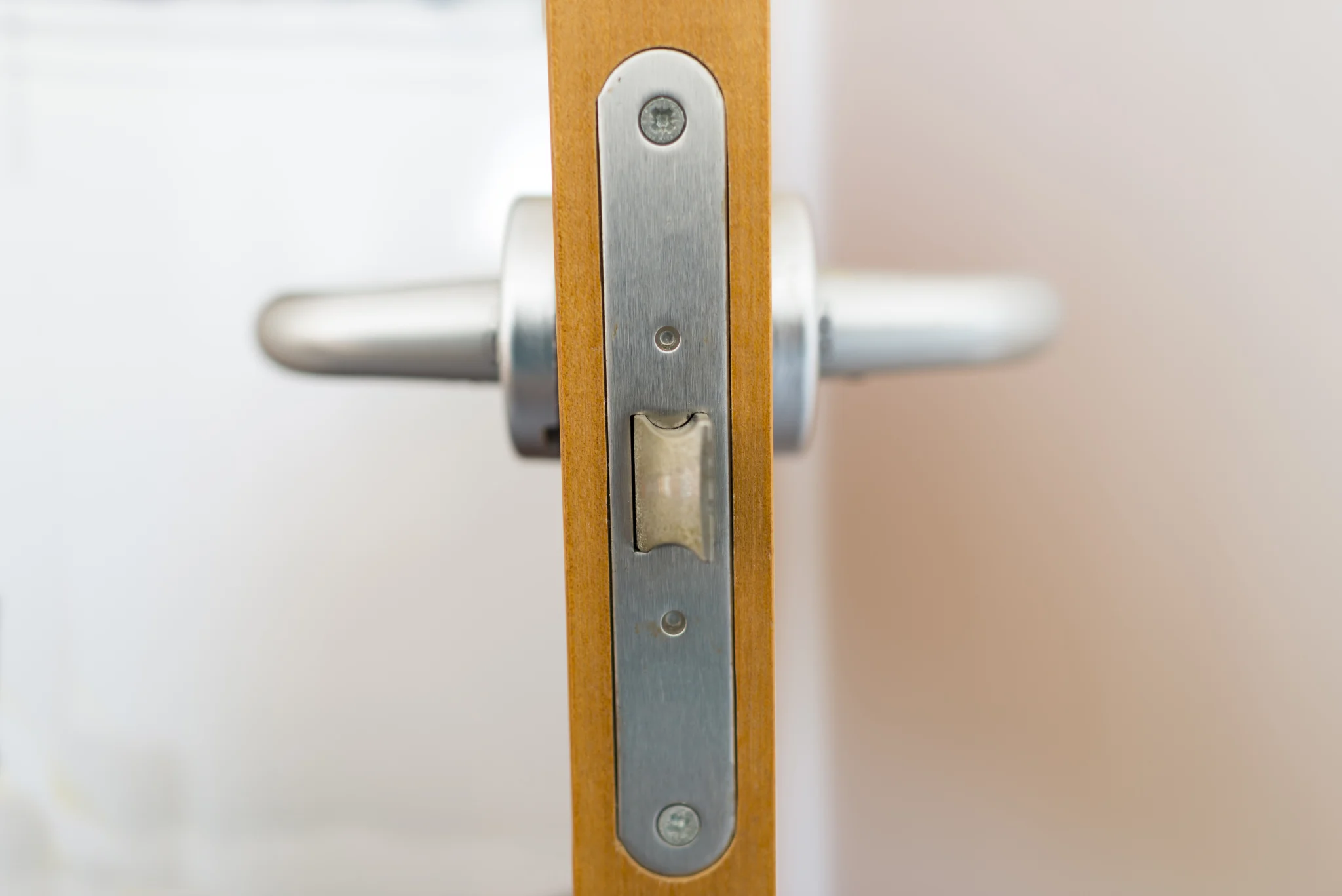 Close-up of a wooden door with a silver handle and latch mechanism.
