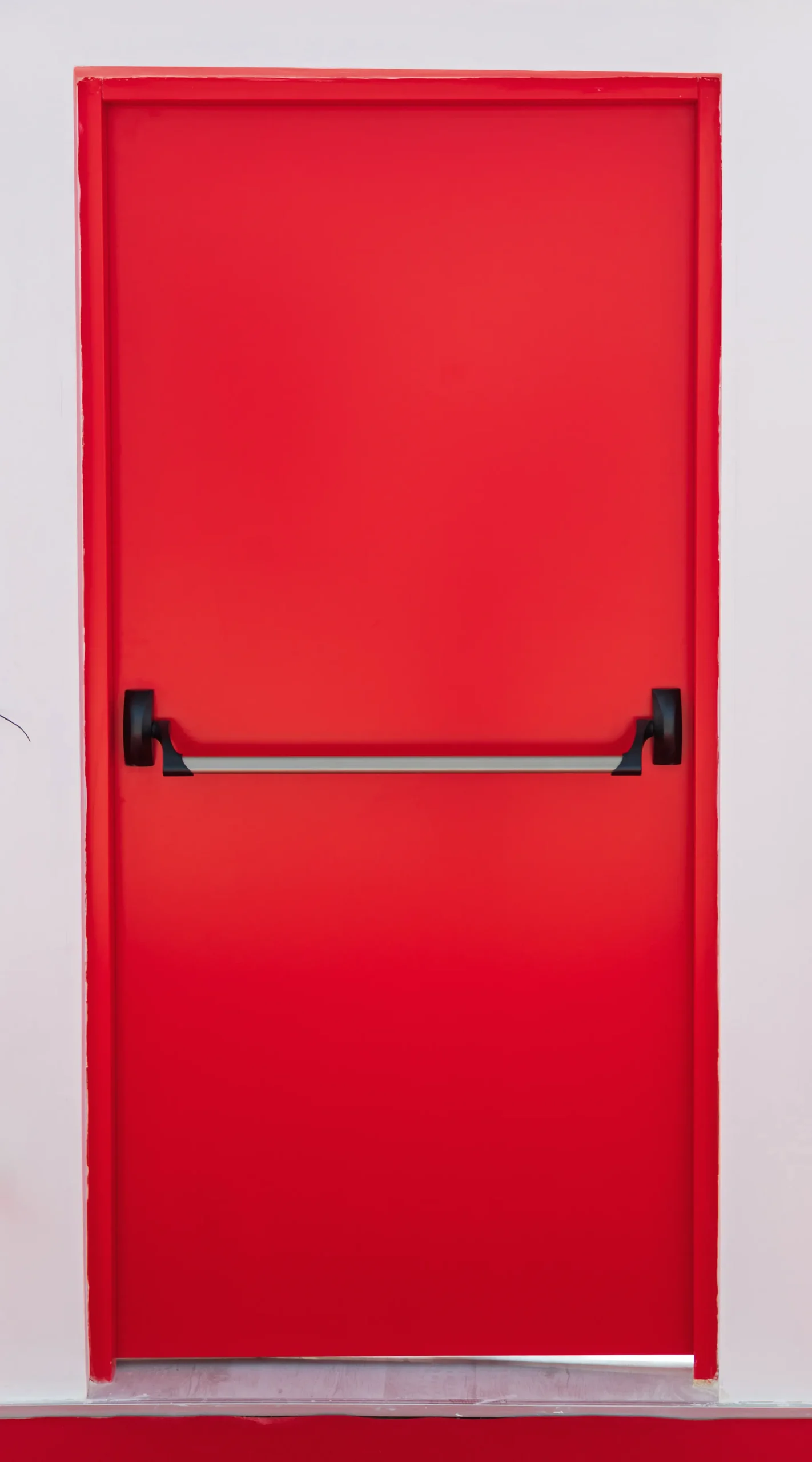 Red fire exit door with a horizontal push bar handle