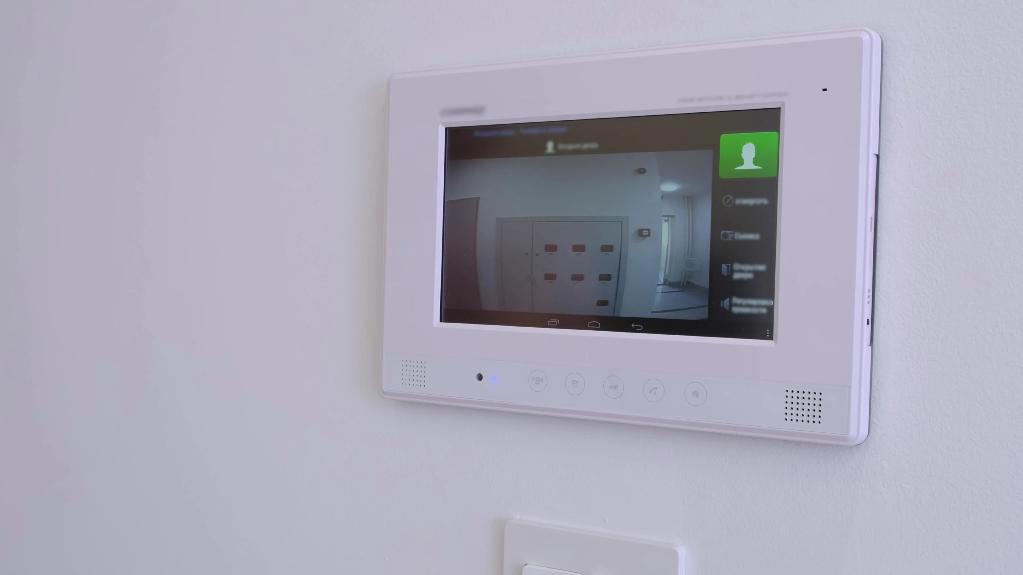 White video intercom system with a screen displaying a hallway view.