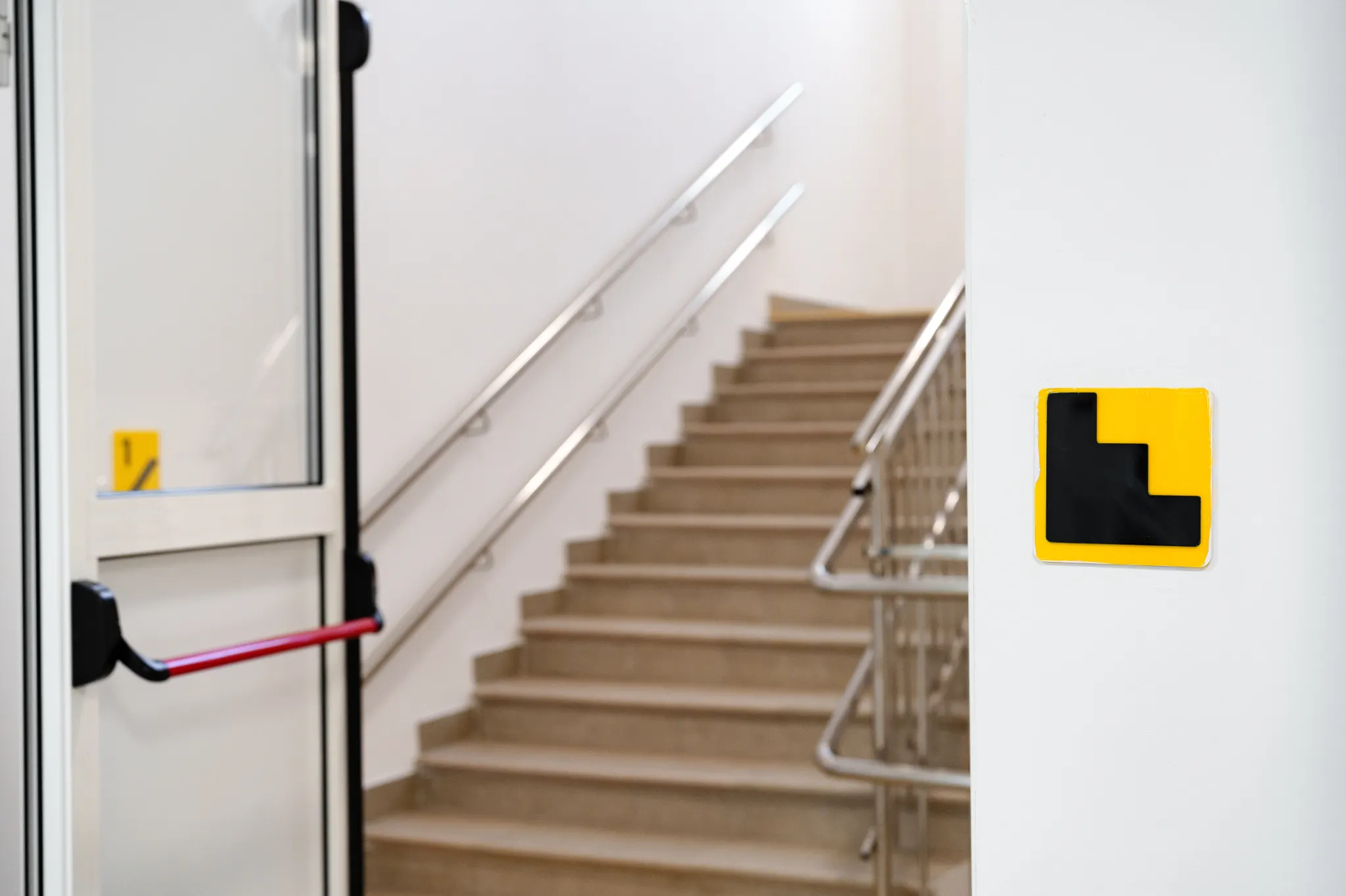 Emergency exit door and staircase with a yellow and black sign