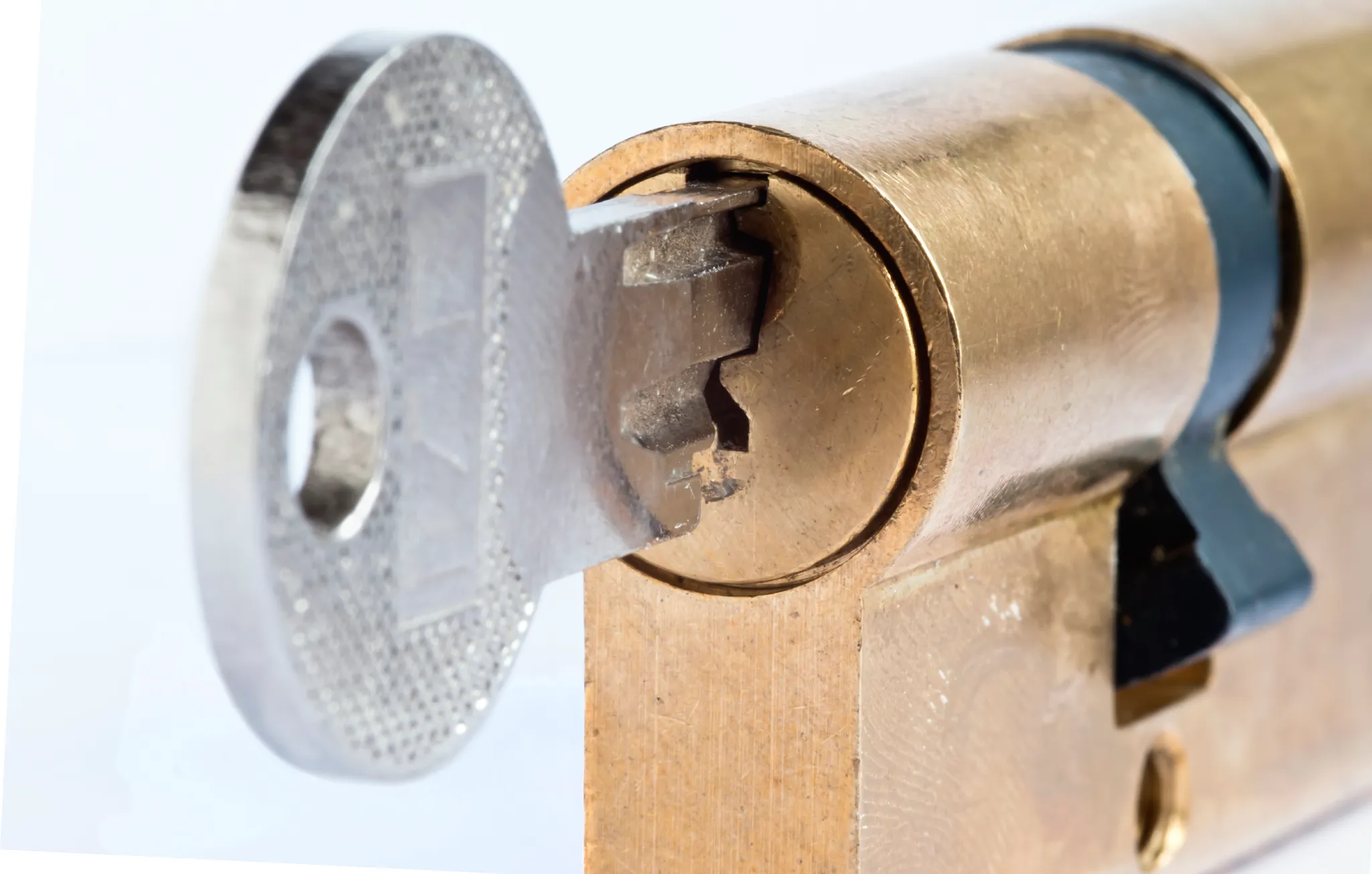 Close-up of a silver key inserted into a brass lock cylinder.