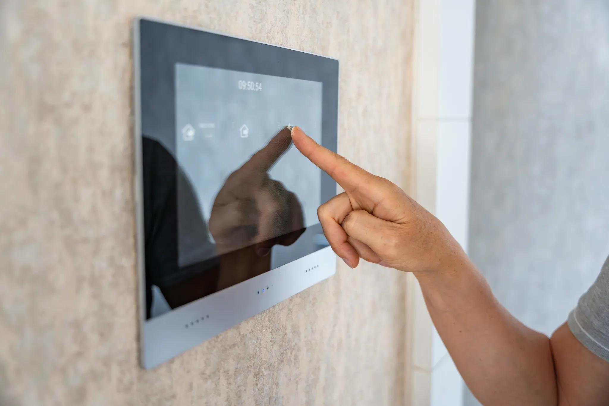 Hand touching a smart home control panel on a wall