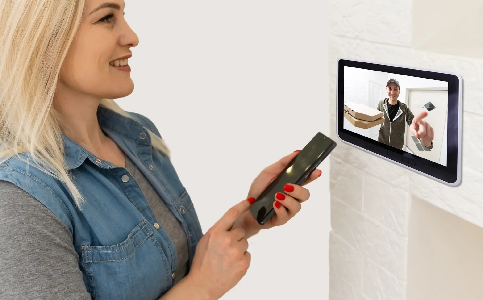 Woman with phone looking at video intercom showing delivery person